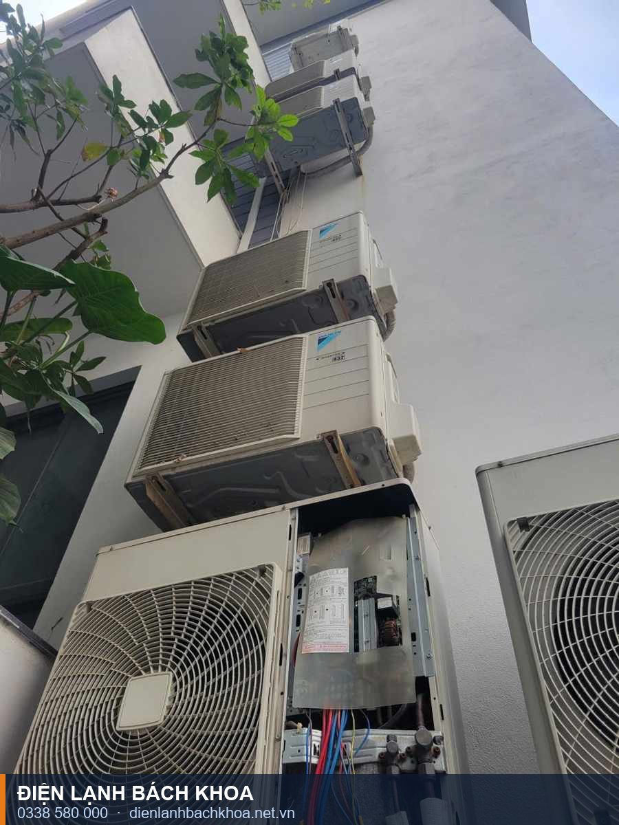Cụm dàn nóng điều hòa lắp ngoài tòa nhà tại Hà Nội, một máy đang mở panel điện để kiểm tra