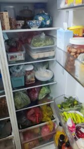 Ngăn mát tủ lạnh chứa đầy thực phẩm xếp kín các tầng kệ và ngăn rau củ