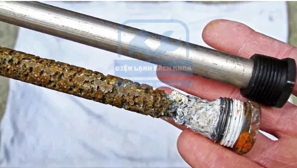 Thanh đốt bình nóng lạnh bám lớp cặn canxi dày màu nâu vàng đặt cạnh một thanh đốt còn sạch để so sánh