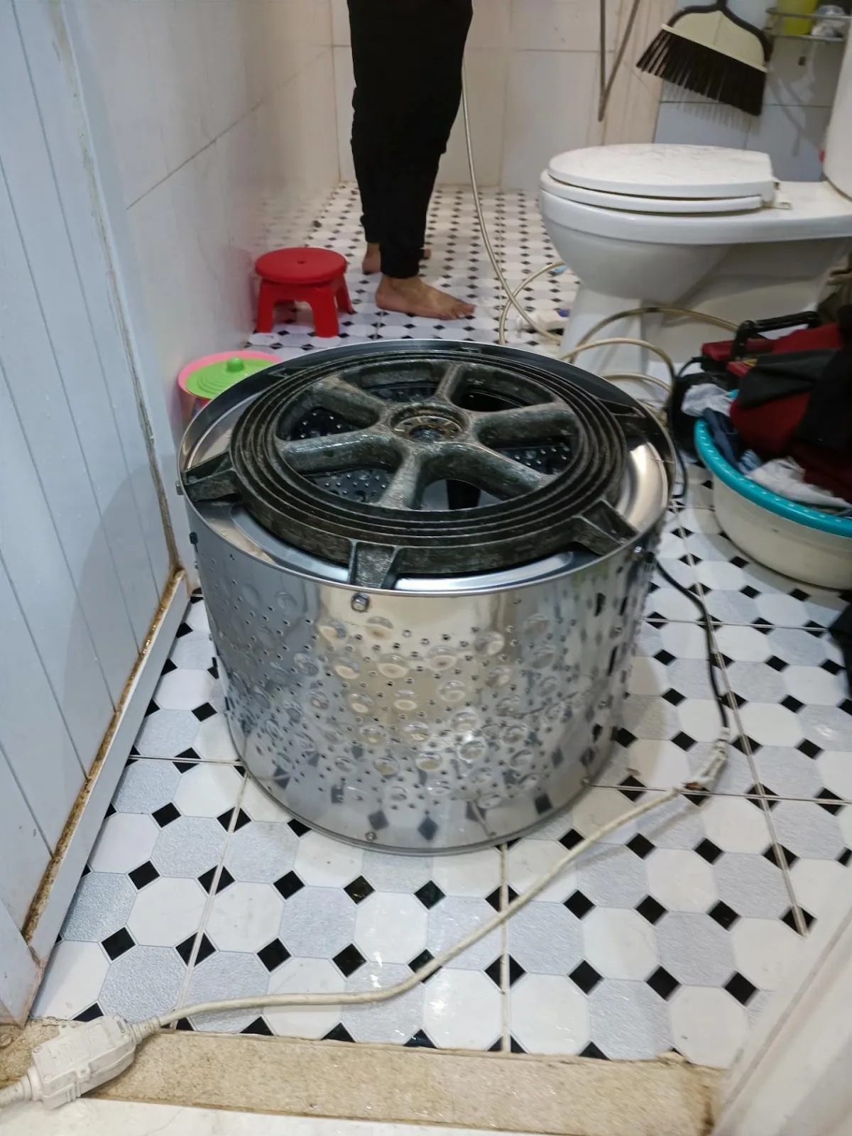 Lồng trong máy giặt lồng đứng đã vệ sinh sạch, úp trên sàn nhà tắm, lộ mâm đỡ và trục quay