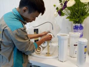 Thợ đổ vật liệu lọc đã bẩn ra khỏi cốc lọc, bên cạnh là ba lõi lọc mới chờ thay